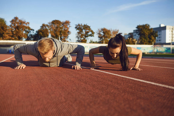 Young couple doing pushups in the stadium - Fotoğraf, Görsel