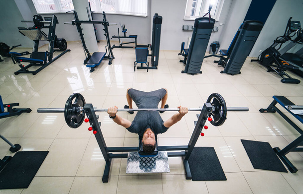 Bodybuilder trainer man doing bench press workout in gym. Photo from the top. Strong abs. Health life sport concept. - Photo, Image
