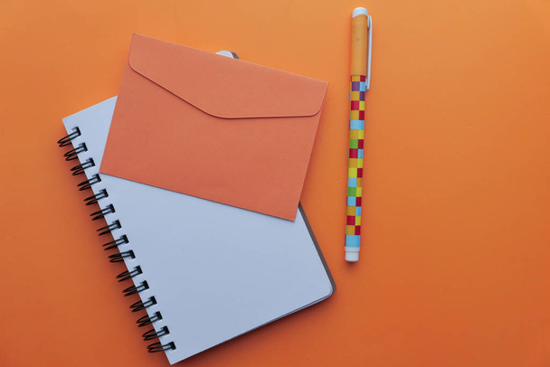 orange color envelope, pen and notepad  - Photo, image