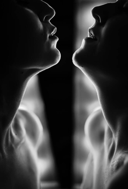 Silhueta de duas mulheres face a face. Contra o fundo de lâmpadas brilhantes
. - Foto, Imagem