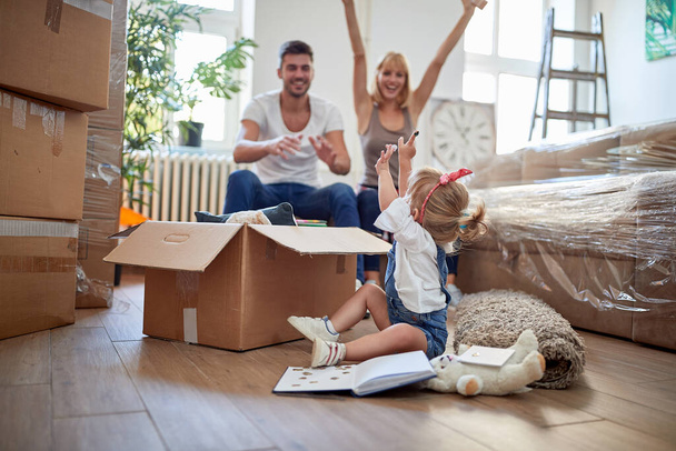 parents playing with their daughter in new apartment, while unpacking.  new apartment, new beginning, joy, playful, carefree, excitement  concept - 写真・画像