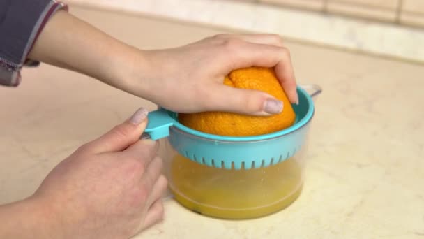 Μια γυναίκα συμπιέζει χυμό από ένα πορτοκάλι. Μια γυναίκα χρησιμοποιεί αποχυμωτή. Τα χέρια κοντά.. - Πλάνα, βίντεο