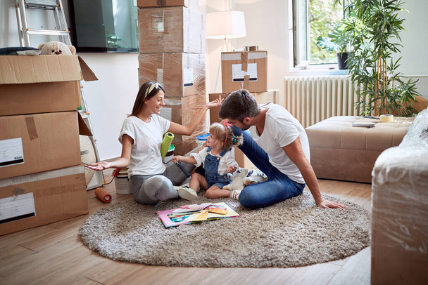giovane famiglia di tre persone che gioca su un tappeto in un nuovo appartamento. nuovo appartamento, nuovo inizio, gioia, concetto di felicità
 - Foto, immagini
