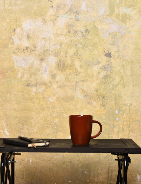 cup with copybook and pen on beige textured background, copy space - 写真・画像