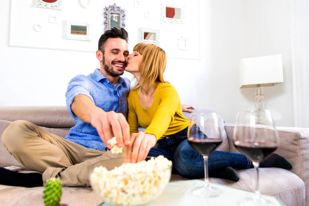 Zwei junge Erwachsene zu Hause - Schönes Paar entspannt sich und schaut einen Film im Fernsehen - Foto, Bild