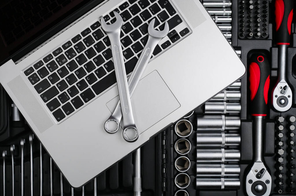servis údržba stříbrný chrom klíč a klíč ležící na notebooku na nářadí s profesionální auto auto nástroje pro opravy - Fotografie, Obrázek
