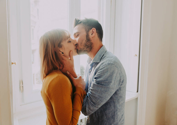 Two young adults at home - Romantic moment at home, couple of lovers kissing - Photo, Image