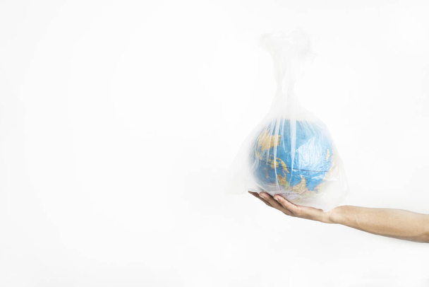 Man hand holding globe with plastic bag, isolated on white background - Photo, Image
