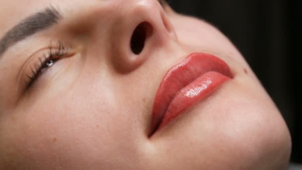 La cara de una chica joven y hermosa. Resultado final del maquillaje labial permanente. Chica luz labios rojos de cerca
 - Metraje, vídeo