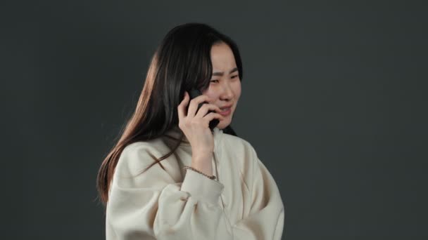 Woman with asian appearance sort things out, swears with somebody by mobile phone. Girl nervous, expresses discontent and resentment. - Felvétel, videó