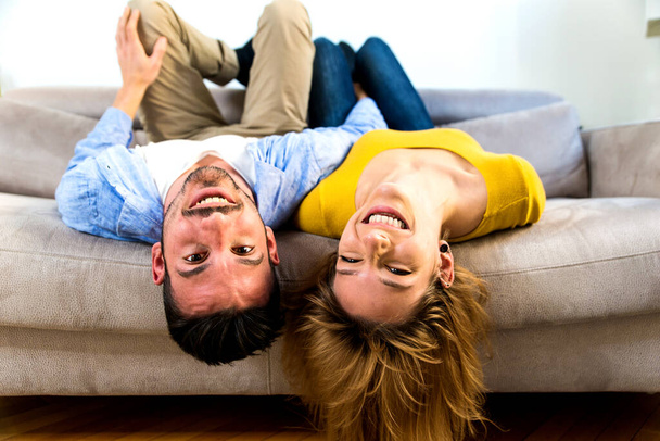 Two young adults at home - Couple of lovers having fun on the sofa - Photo, Image