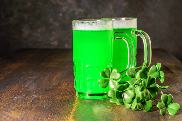 Kupalar dolusu yeşil bira ve ahşap arka planda bir yonca dalı. Aziz Patrick Günü 'nü kutlamak - Ulusal Geleneksel Bayram.  - Fotoğraf, Görsel