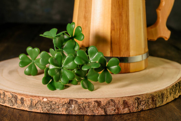 Details of symbols of Saint Patrick Day - leaves of sahmrock and a mug of green beer on the wooden background. Celebrating irish traditional St. Patrick's Day.  - Photo, Image