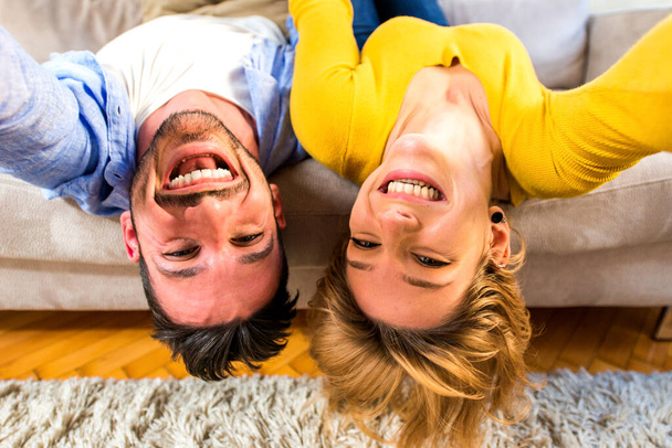 Zwei junge Erwachsene zu Hause - Liebespaar amüsiert sich auf dem Sofa - Foto, Bild