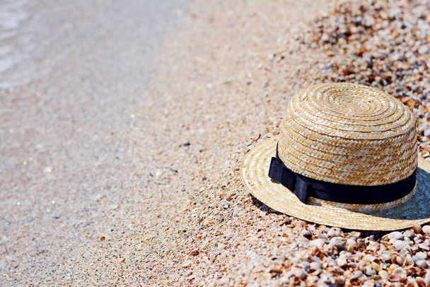 砂の上に帽子をストロー、太陽の保護コンセプト。砂浜を背景にした女性用ビーチアクセサリーや夏服. - 写真・画像