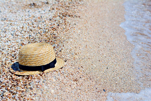 Szalmakalap homokon, napvédő koncepció. Női strandkiegészítők vagy nyári ruha homokos alapon. - Fotó, kép