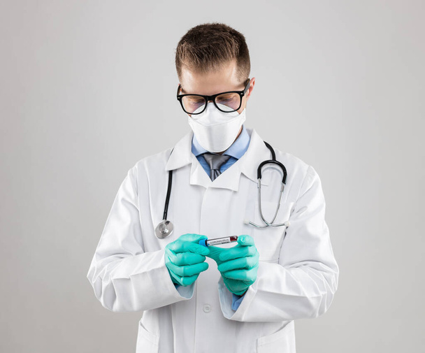 Γιατρός με αναπνευστική μάσκα και κρατώντας το δείγμα αίματος Coronavirus Covid-19  - Φωτογραφία, εικόνα