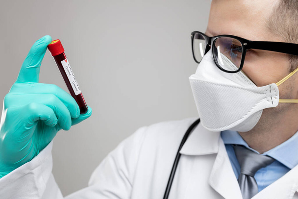 Doctor wearing respiratory mask and holding the Coronavirus Covid-19 blood sample  - 写真・画像