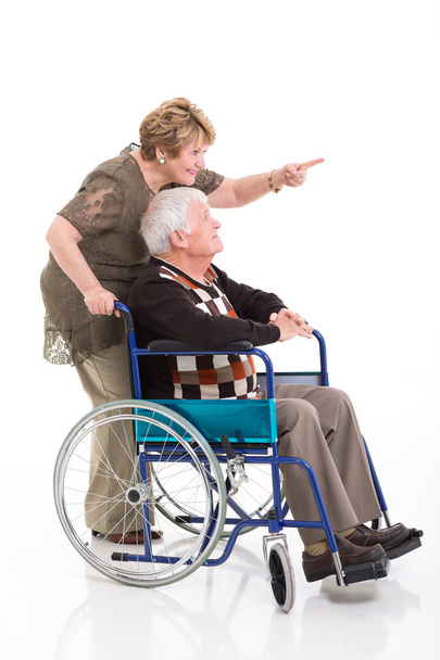 senior woman behind disabled husband and pointing - Foto, Bild