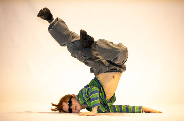 pieni poika ainutlaatuisessa tanssiasennossa, vaikea akrobaattinen asema, iloinen poika, poikkeuksellinen lapsi
 - Valokuva, kuva