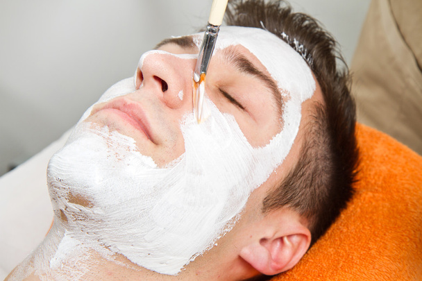 Thérapeute appliquant un masque facial à un beau jeune homme dans un spa
 - Photo, image