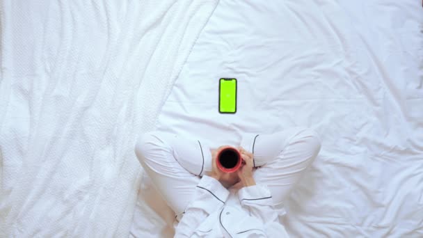 bovenaanzicht vrouw houden rode beker kijken op display mobiele zit in slaapkamer - Video