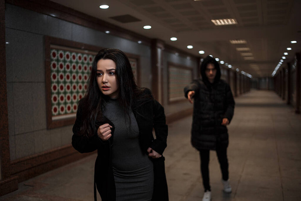 Genç ve güzel bir kadın siyah elbiseli bir soyguncunun elinden kaçmaya çalışıyor. Altgeçitte. Geceleyin - Fotoğraf, Görsel