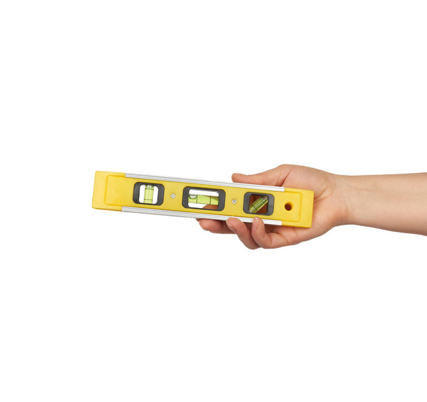 жіноча рука тримає пластиковий інструмент жовтого рівня з капсулами ізольовані на білому тлі, крупним планом
 - Фото, зображення