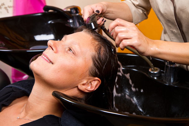 Hairdressers hand washing female customer's hair in salon - Fotoğraf, Görsel