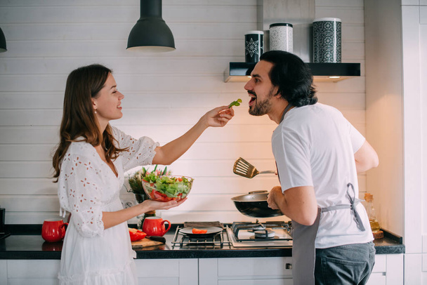 Internationale Vrouwendag. Jong stel in de ochtend in de keuken thuis. Een man kookt een vrouw een feestelijk ontbijt op 8 maart in een mooie stijlvolle keuken. - Foto, afbeelding