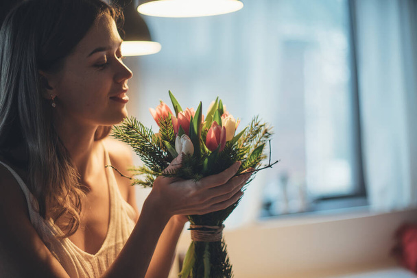 Wiosenny bukiet kwiatów w rękach kobiety. Międzynarodowy Dzień Kobiet. Młoda dziewczyna wpada w ręce tulipanów. - Zdjęcie, obraz