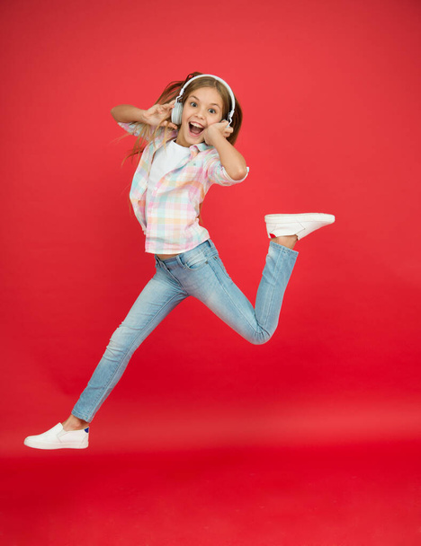 Jumping mid air. Happy small girl dancing. Cute child enjoying happy dance music. Music is happiness for her. Easy listening music. Small girl listening to music in headphones. Dancing girl - Photo, Image