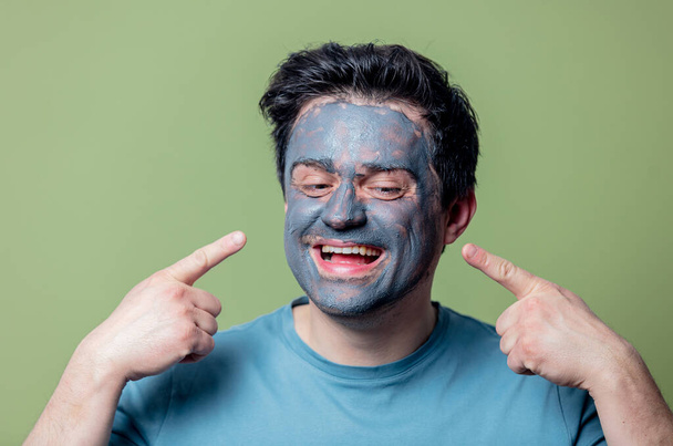 guy in a face care mask on a green background - Foto, afbeelding