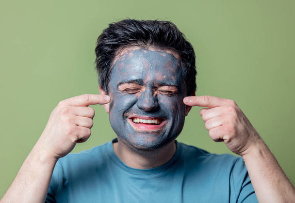 guy in a face care mask on a green background - Zdjęcie, obraz