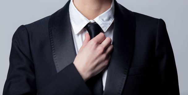ビジネスの女性はグレーの背景で黒いネクタイを調整し  - 写真・画像