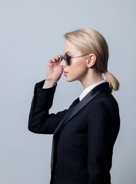Стильная деловая женщина в классическом черном деловом костюме и солнечных очках
 - Фото, изображение