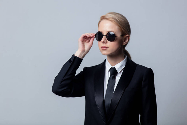 Mujer de negocios de estilo en un traje de negocios negro clásico y gafas de sol
 - Foto, Imagen