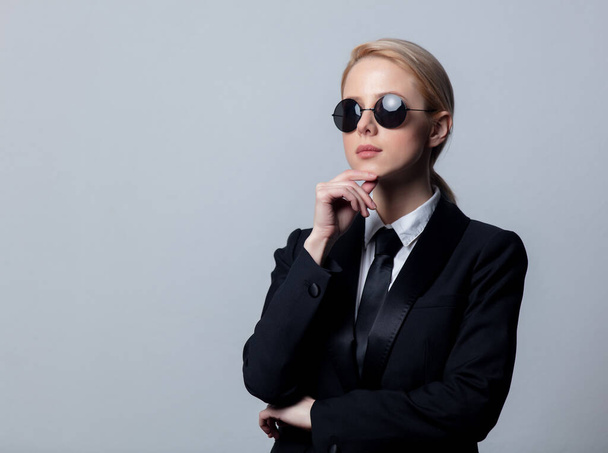Klasik siyah takım elbiseli ve güneş gözlüklü bir iş kadını. - Fotoğraf, Görsel