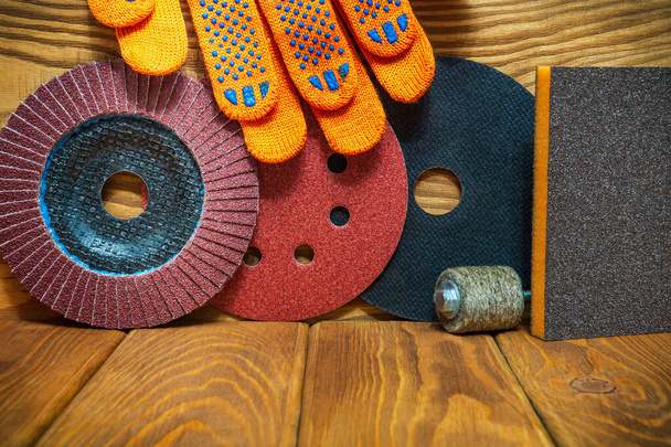 Set von Schleifwerkzeugen und Arbeitshandschuhen auf einem alten Holzbrett-Assistenten wird zum Schleifen von Gegenständen verwendet - Foto, Bild