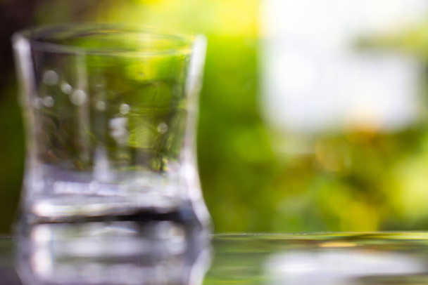 Blurred transparent glass of clean water on reflection  texture in bokeh green garden background, Close up & Macro shot, Selective focus, Healthy Drink concept - Foto, imagen
