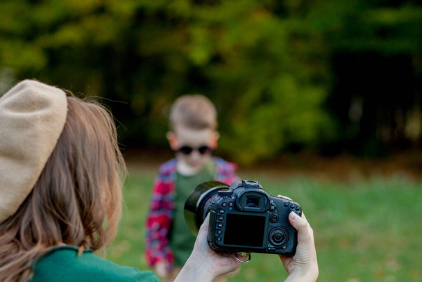 Woman photographer photographing the child to spend outside in the park. - 写真・画像