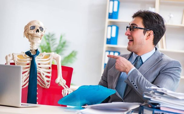 Zakenman werkt met skelet in kantoor - Foto, afbeelding