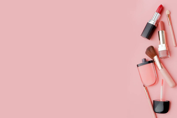 Женский стол с декоративной косметикой для макияжа на розовом фоне
 - Фото, изображение