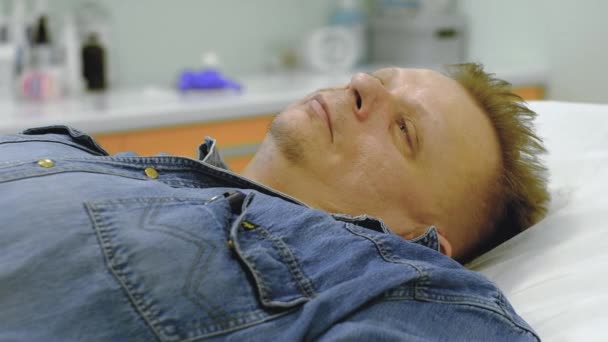 a man in a denim suit is given intravenous therapy - Filmmaterial, Video