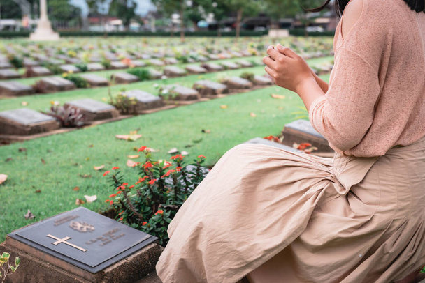 Close-Up of Religious Christian Woman Hands Clasped While Honoring and Praying to Military in War Cemetery. Teenager Woman in Expression Sadness and Pray for Soldier Prisoner of War in Tomb. - Zdjęcie, obraz