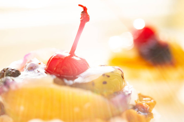 Torta con frutta e ciliegia primo piano sul tavolo soleggiato
 - Foto, immagini