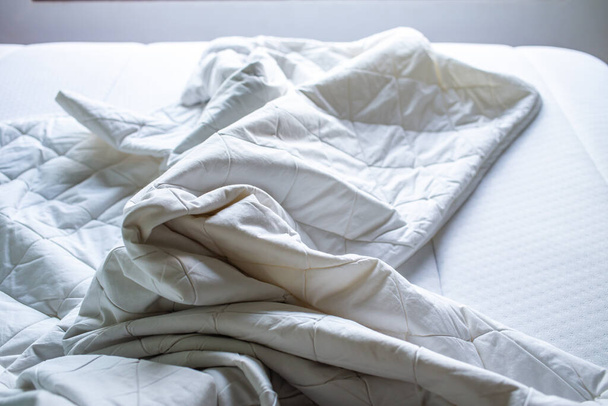 Sábana blanca arrugada en cama blanca, Primer plano, enfoque selectivo, concepto de limpieza de dormitorios
 - Foto, Imagen