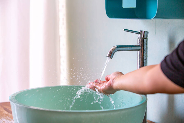 Eau qui coule du robinet à la main, Lavabo vert, Concept salle de bain
 - Photo, image