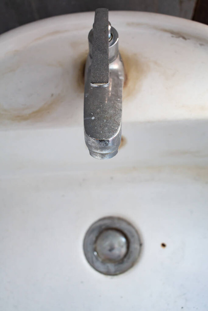 Старый кран и грязная белая раковина, засоренная канализация, концепция очистки ванной комнаты
 - Фото, изображение
