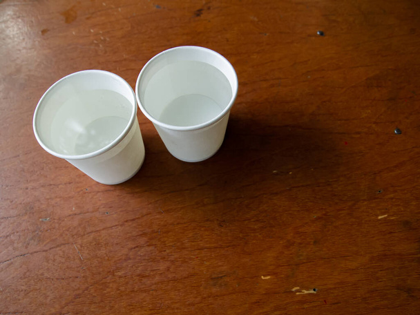 Две бумажные чашки воды на фоне деревянного стола, Закрыть и макроснимок
 - Фото, изображение